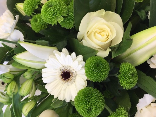 White and green hand-tied bouquet with lilies, roses, germini and green chrysanthemums presented in a gift bag.