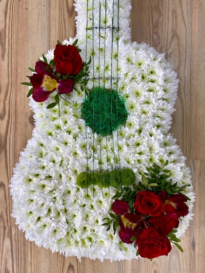 Guitar-shaped funeral tribute made with white chrysanthemum, mixed floral focal in chosen colours, and detailed with grass strings and Kermit chrysanthemum tuning pegs, measuring approximately 97cm high by 38cm wide.