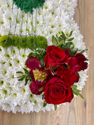 Guitar-shaped funeral tribute made with white chrysanthemum, mixed floral focal in chosen colours, and detailed with grass strings and Kermit chrysanthemum tuning pegs, measuring approximately 97cm high by 38cm wide.