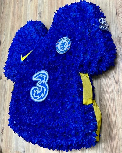 Chelsea FC shirt funeral tribute with chrysanthemum base, pipework accents and waterproof printed crests, 21 x 21 inches, available in retro and modern shirt versions.