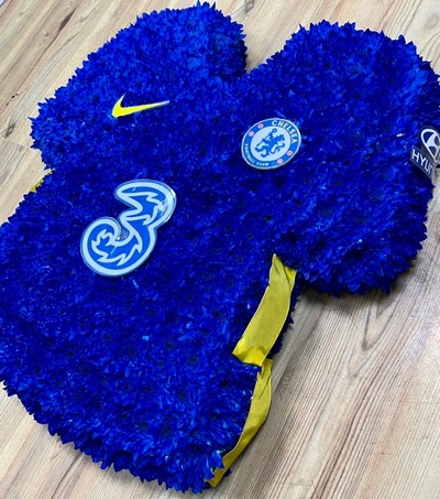 Chelsea FC shirt funeral tribute with chrysanthemum base, pipework accents and waterproof printed crests, 21 x 21 inches, available in retro and modern shirt versions.
