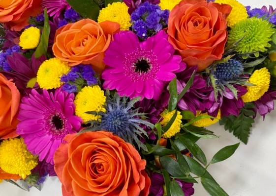 Star-shaped funeral tribute with vibrant seasonal flowers and fresh foliage for added texture.