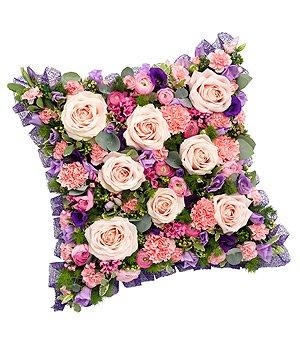 Cushion-shaped funeral tribute in pink, mauve, and purple with luxury flowers and soft mixed foliage.