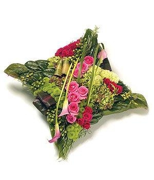 Pink and green cushion funeral tribute with luxury flowers and soft textured foliage.