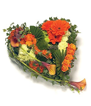 Contemporary heart-shaped funeral tribute in gold and orange with luxury flowers and textured foliage.