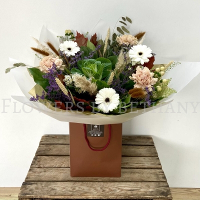 Woodland Whisper bouquet with white gerbera, blush carnations, berries and autumn grasses in natural gift wrap.