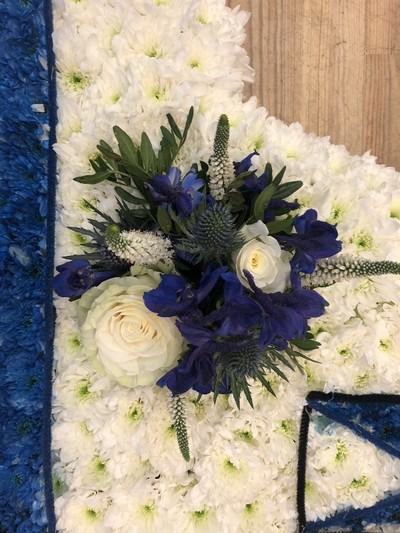 Caravan-shaped funeral tribute made with white chrysanthemum, sprayed detailing, and laminated accents, finished with optional mixed floral focal in chosen colours, measuring approximately 89cm x 51cm.