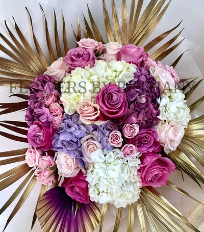 Luxury bouquet of roses, spray roses and hydrangea with gold leaf and ombré palm, presented in a pink gift bag.