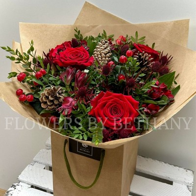 Ruby red seasonal bouquet with festive tones, rustic kraft wrap and signature gift bag.