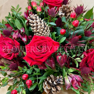 Ruby red seasonal bouquet with festive tones, rustic kraft wrap and signature gift bag.