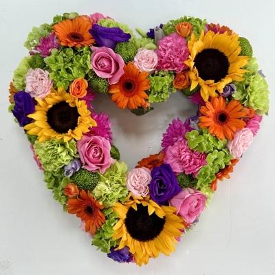 Heart-shaped funeral tribute featuring luxury summer-toned flowers in a vibrant mixed floral arrangement.