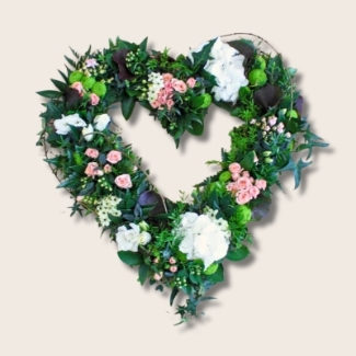 Open textured funeral heart tribute with natural foliage and soft white and pink flowers for an organic look.