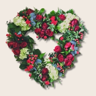 Textured open heart funeral tribute in red with luxury flowers and natural mixed foliage.