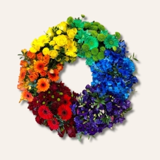 Vibrant funeral wreath with mixed seasonal flowers arranged in a rainbow pattern of red, orange, yellow, green, blue, and purple.
