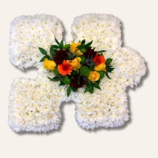 Puzzle piece funeral tribute with white chrysanthemum base and customisable focal flower.