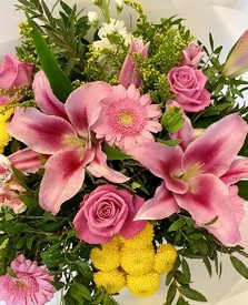 Pink and yellow seasonal florist’s choice hatbox arrangement with mixed florals and greenery.
