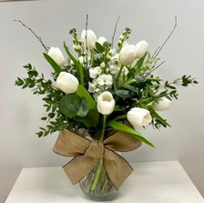 White Christmas vase arrangement with tulips, scented stocks, birch, mixed foliage and natural bow in a clear glass vase.