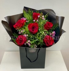 Bouquet featuring 6 luxury red roses with a filler florals, accented with diamanté in the roses, complemented by foliage, wrapped in luxury cellophane and matching gift bag, hand-tied in water.