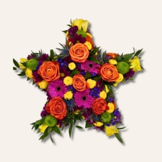 Star-shaped funeral tribute with vibrant seasonal flowers and fresh foliage for added texture.