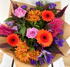 Summer Sunset bouquet with orange roses, purple clematis and pink astilbe, hand-tied in luxury gift wrap.