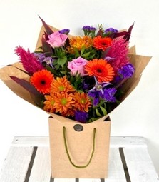Summer Sunset bouquet with orange roses, purple clematis and pink astilbe, hand-tied in luxury gift wrap.