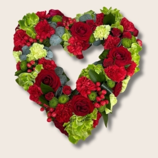 Cherry heart funeral tribute in red and green with luxury floral varieties and seasonal accents.
