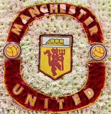 Manchester United badge-shaped funeral tribute made with white and yellow chrysanthemum, red carnations, and pipe cleaner with laminated detailing on a 24