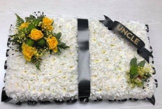 Open Prayer Book funeral tribute with white chrysanthemum base, yellow floral focal and foliage, 31 x 61 cm, customisable ribbon and flowers.