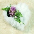 Heart-shaped funeral tribute made of soft white feathers, accented with lilac flowers and mixed foliage.