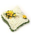 White chrysanthemum massed cushion funeral tribute with foliage edging and customisable ribbon and flower colours.