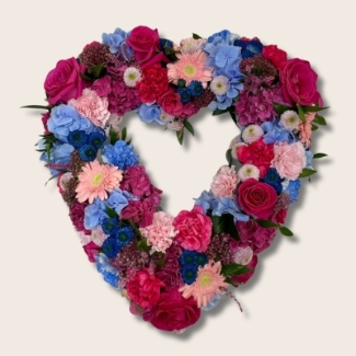 Open heart funeral tribute in pink and blue sapphire tones with luxury flowers and seasonal accents.