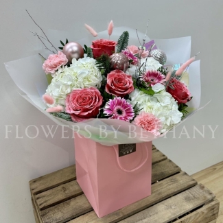 Pink Christmas bouquet with snowy glitter roses, white hydrangea, silver birch, seasonal pink florals and pink baubles, wrapped in iridescent cellophane.