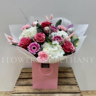 Pink Christmas bouquet with snowy glitter roses, white hydrangea, silver birch, seasonal pink florals and pink baubles, wrapped in iridescent cellophane.
