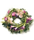 Loose funeral wreath in pink and green shades, featuring mixed luxury florals and complemented with foliage.